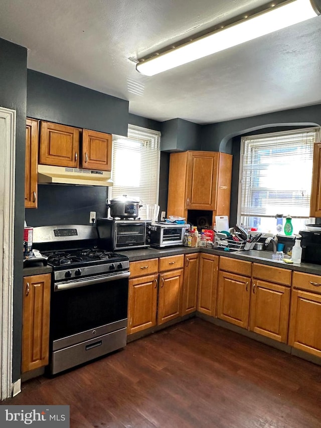 kitchen with dark wood-type flooring, gas stove, and a healthy amount of sunlight