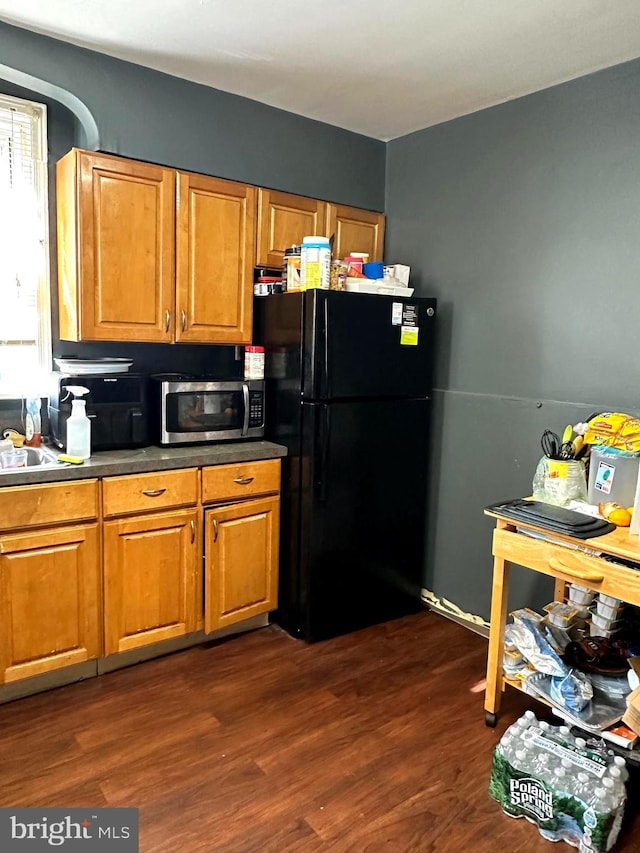 kitchen featuring dark wood-type flooring and black fridge