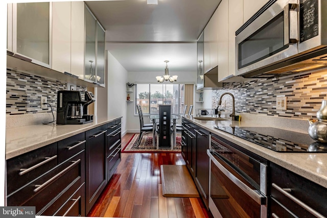 kitchen featuring appliances with stainless steel finishes, sink, a chandelier, white cabinetry, and hanging light fixtures