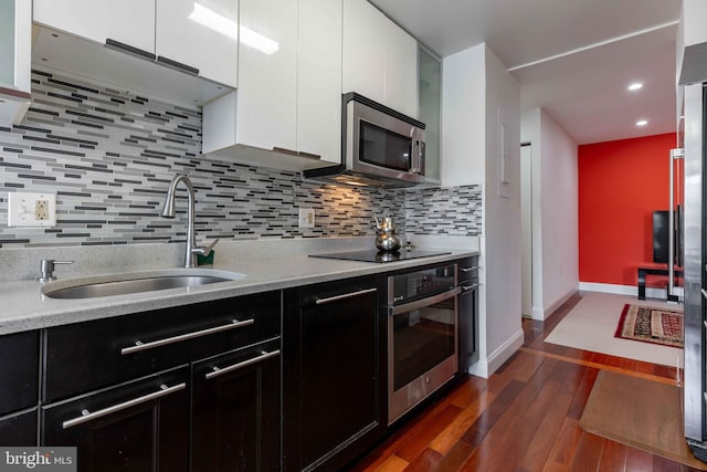 kitchen with white cabinets, sink, decorative backsplash, appliances with stainless steel finishes, and dark hardwood / wood-style flooring