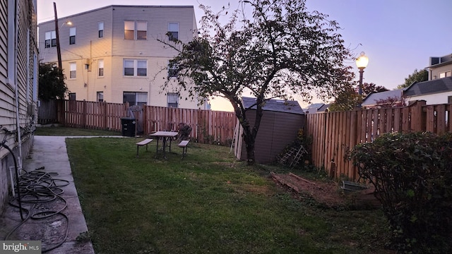 yard at dusk featuring a storage unit