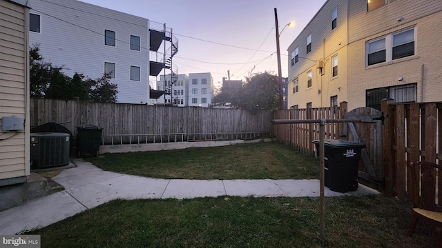 yard at dusk featuring central AC