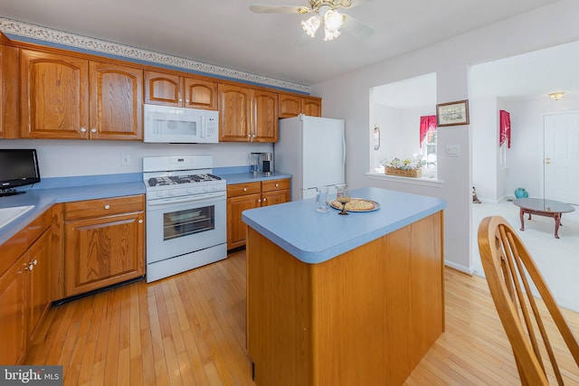 kitchen with a center island, light countertops, light wood-style flooring, brown cabinetry, and white appliances