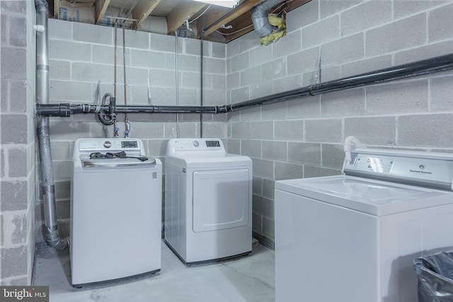 laundry area with concrete block wall, laundry area, and separate washer and dryer