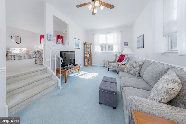 carpeted living room with a ceiling fan, baseboards, and stairs