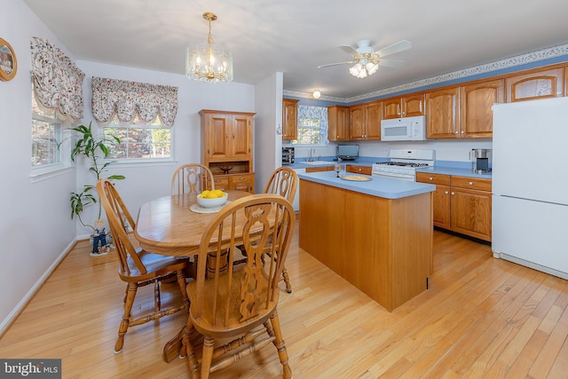 kitchen with white appliances, a center island, light countertops, hanging light fixtures, and brown cabinets