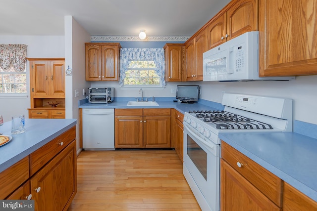 kitchen with light countertops, white appliances, a sink, and brown cabinets