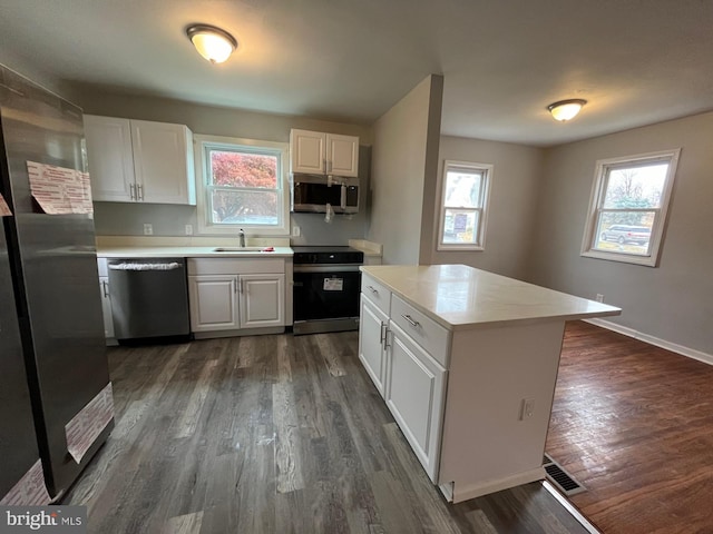 kitchen featuring dark wood-type flooring, white cabinets, a healthy amount of sunlight, and appliances with stainless steel finishes