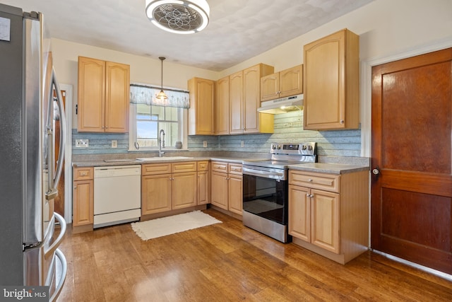 kitchen featuring appliances with stainless steel finishes, sink, light brown cabinets, pendant lighting, and light hardwood / wood-style flooring