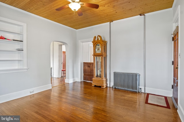 unfurnished living room with radiator, crown molding, built in features, and hardwood / wood-style flooring