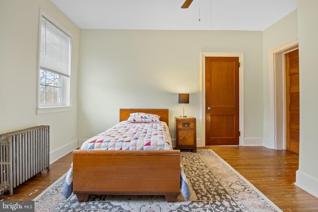 bedroom featuring hardwood / wood-style floors, ceiling fan, and radiator