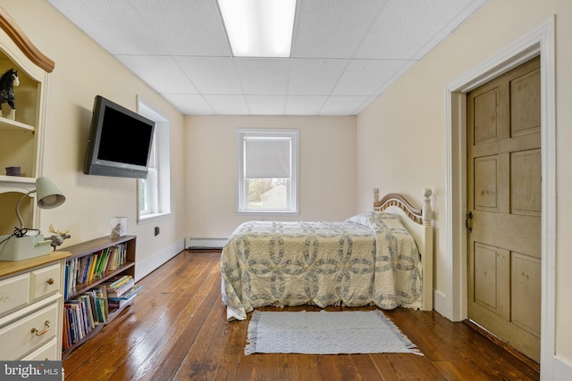 bedroom featuring a paneled ceiling, dark hardwood / wood-style floors, and a baseboard radiator