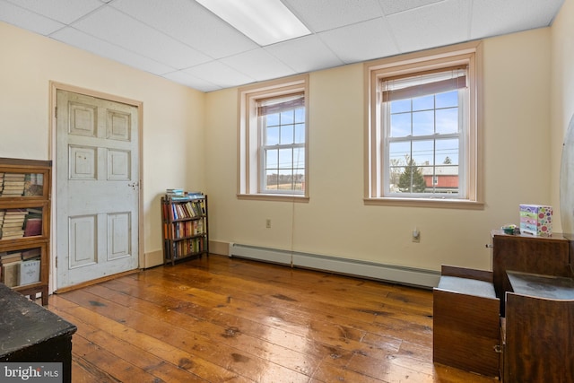 interior space with a paneled ceiling, a baseboard radiator, and dark wood-type flooring