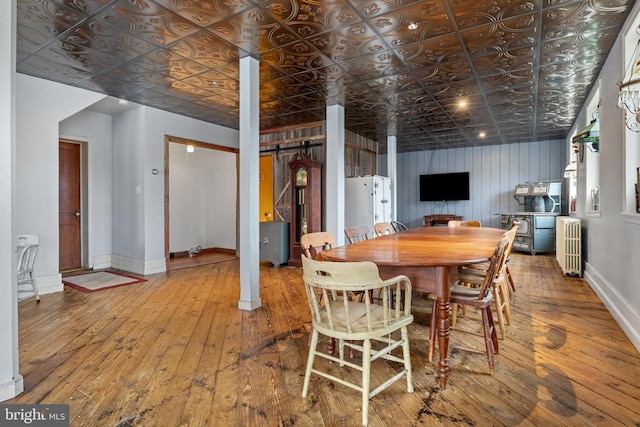 dining area featuring a barn door, wood-type flooring, and radiator