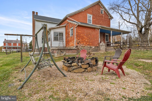 back of property with a yard and an outdoor fire pit