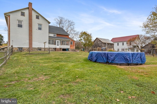 rear view of property with a lawn, a sunroom, and a covered pool