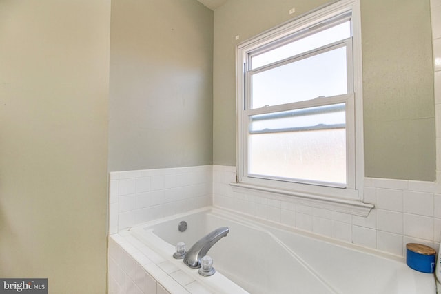 bathroom featuring a wealth of natural light and tiled bath