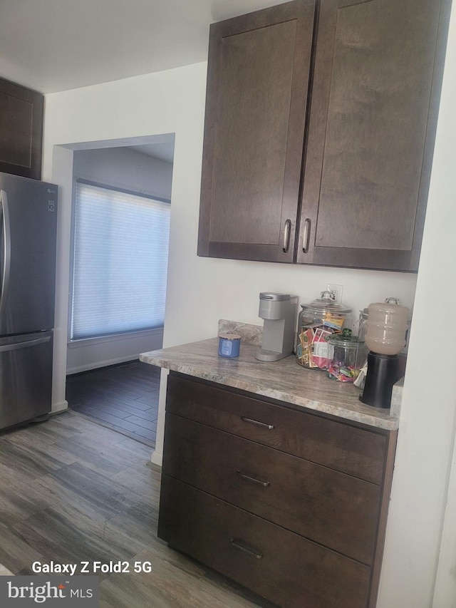 kitchen featuring dark brown cabinetry, stainless steel fridge, and dark hardwood / wood-style floors