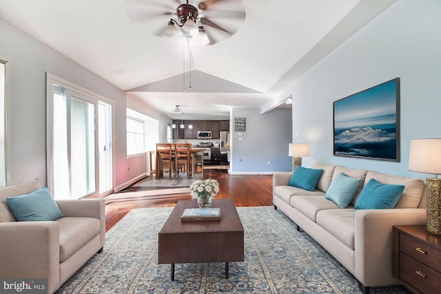 living room with ceiling fan, dark wood-type flooring, and vaulted ceiling