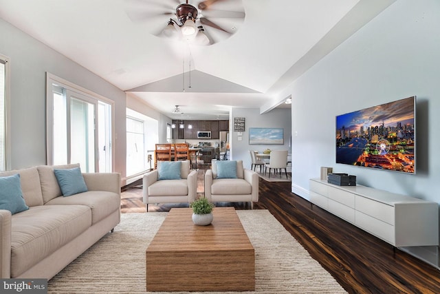 living room featuring ceiling fan with notable chandelier, dark hardwood / wood-style floors, and vaulted ceiling