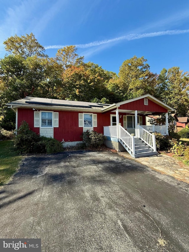 single story home with solar panels and a porch