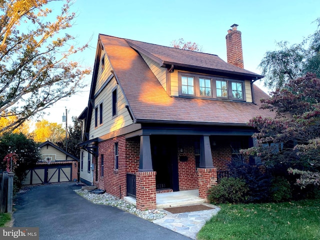 view of front of property featuring an outbuilding, a garage, and covered porch