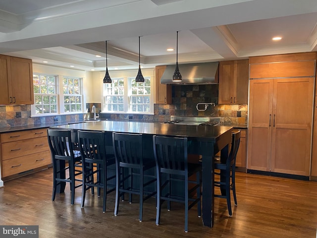 kitchen with wall chimney exhaust hood, dark hardwood / wood-style flooring, and a breakfast bar area