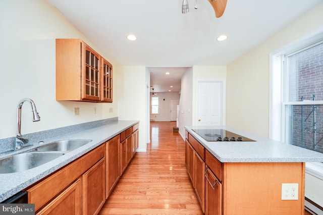 kitchen featuring a kitchen island, black electric cooktop, baseboard heating, sink, and light hardwood / wood-style floors