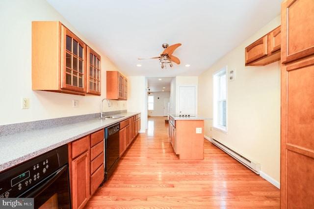 kitchen with baseboard heating, sink, a center island, black appliances, and light hardwood / wood-style floors