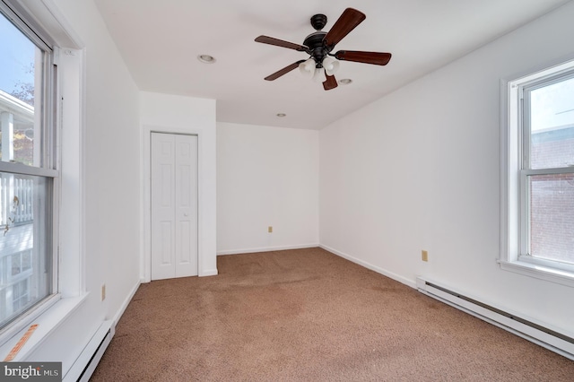 carpeted spare room with ceiling fan, a healthy amount of sunlight, and a baseboard heating unit