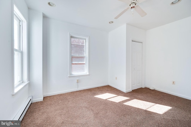 spare room with a baseboard heating unit, carpet floors, a healthy amount of sunlight, and ceiling fan