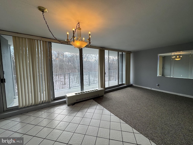 unfurnished dining area featuring a chandelier, tile patterned floors, carpet flooring, baseboards, and radiator