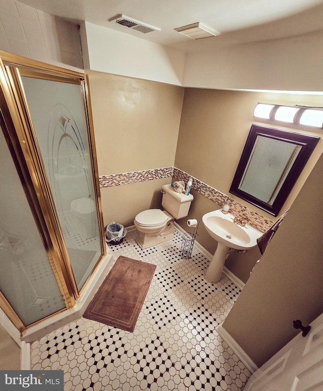 bathroom featuring toilet, tile patterned flooring, sink, and a shower with door