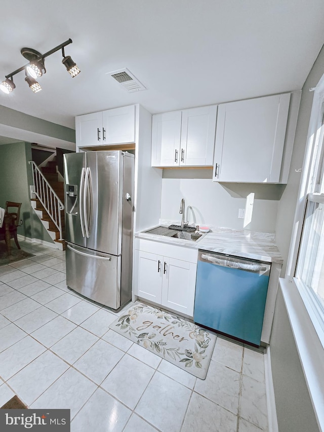 kitchen with white cabinets, stainless steel appliances, sink, and light tile patterned floors