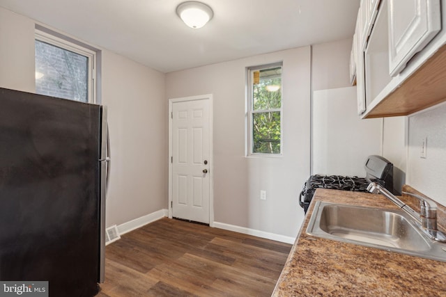 kitchen featuring white cabinets, black fridge, range, dark wood-type flooring, and sink