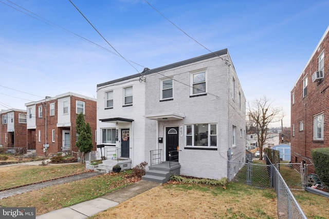 townhome / multi-family property with cooling unit and a front yard