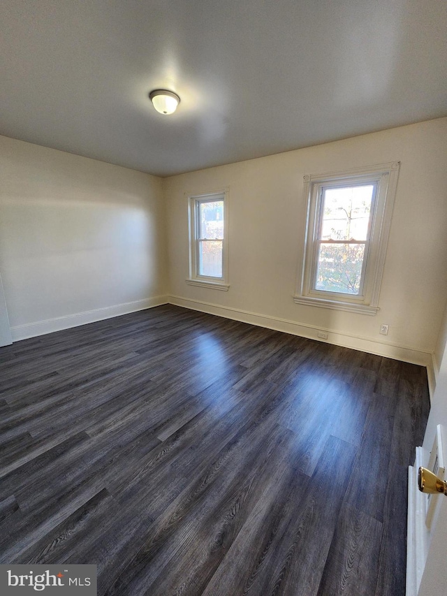 empty room with plenty of natural light and dark hardwood / wood-style flooring