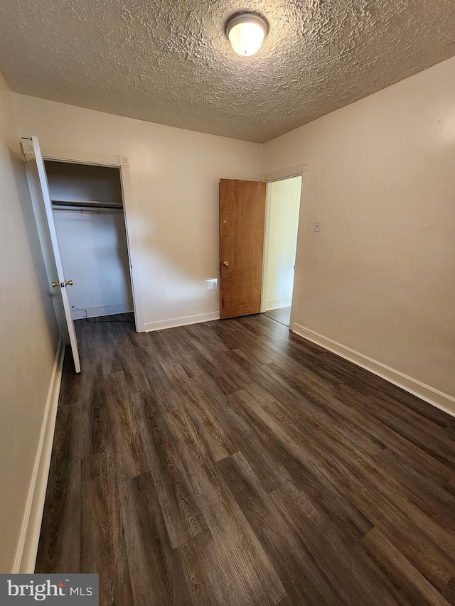 unfurnished bedroom with a closet, dark hardwood / wood-style floors, and a textured ceiling