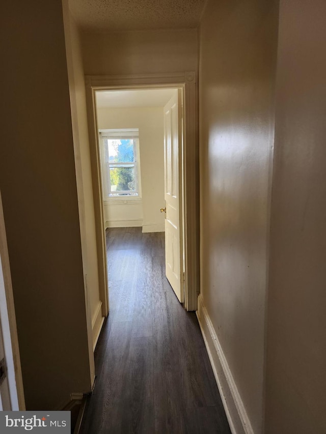 hall featuring a textured ceiling and dark hardwood / wood-style flooring