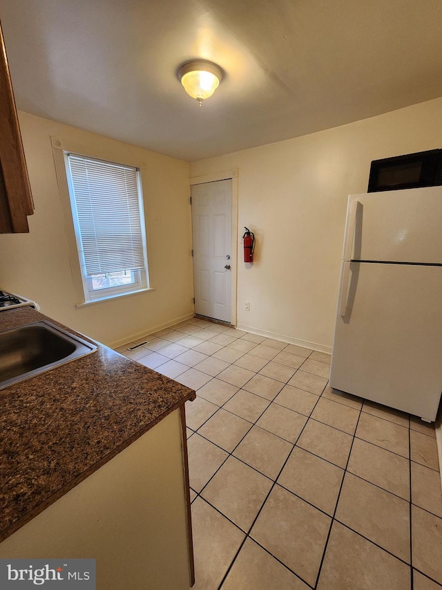 kitchen with sink, light tile patterned flooring, and white fridge