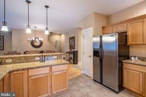 kitchen featuring light brown cabinets, stainless steel fridge with ice dispenser, light stone countertops, a chandelier, and decorative light fixtures