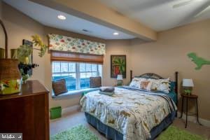 carpeted bedroom with beamed ceiling and ceiling fan