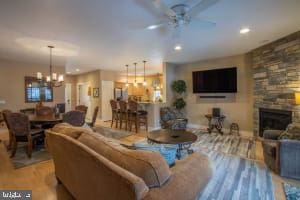 living room with ceiling fan with notable chandelier, light hardwood / wood-style flooring, and a fireplace