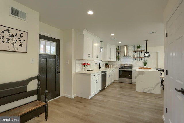 kitchen featuring white cabinetry, stainless steel appliances, light wood-type flooring, and pendant lighting