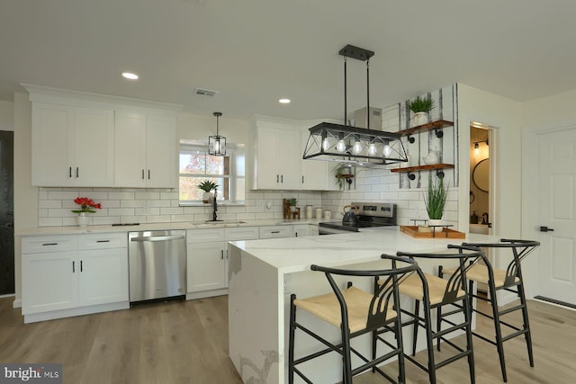 kitchen featuring sink, appliances with stainless steel finishes, pendant lighting, and white cabinetry