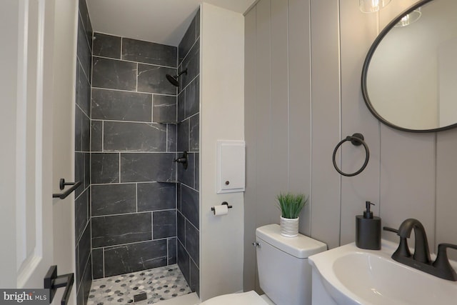 bathroom with toilet, sink, and tiled shower