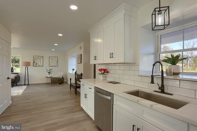 kitchen with backsplash, white cabinetry, light hardwood / wood-style floors, pendant lighting, and stainless steel dishwasher