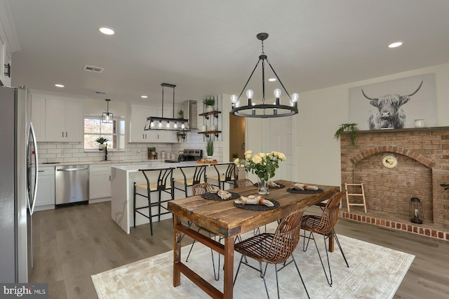 dining area with light hardwood / wood-style floors and a chandelier