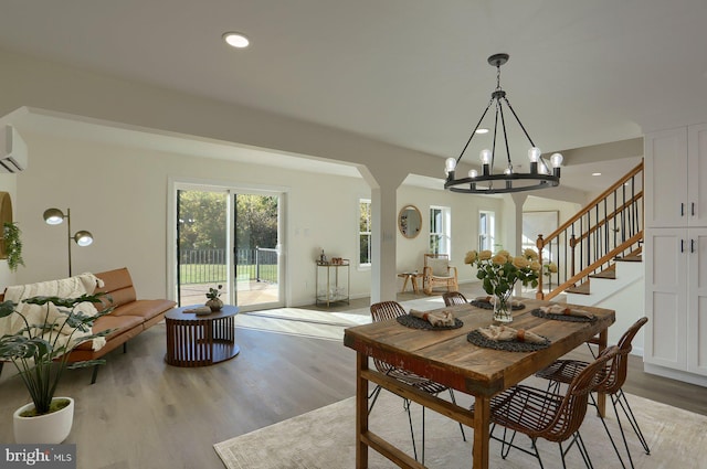 dining room featuring light hardwood / wood-style floors, a notable chandelier, and an AC wall unit