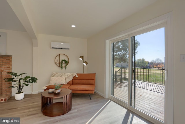 sitting room with a wall mounted AC and light wood-type flooring